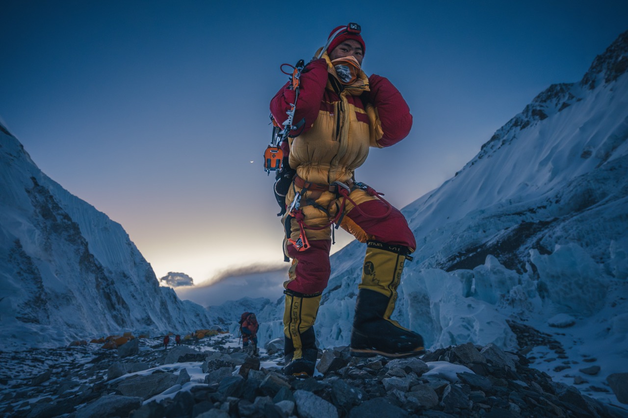 A climber in a full down suit at base camp before dawn