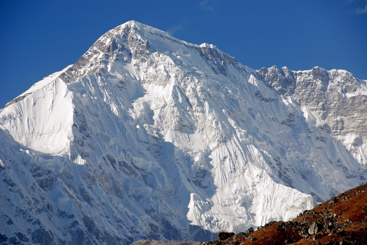 A steep snow face rising under a clear blue sky