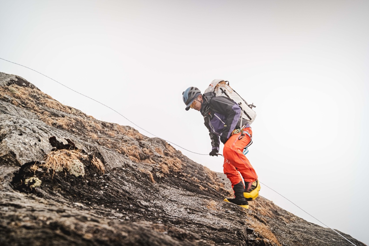 A climber working down a rock slab on a fixed line